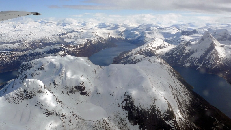 Nous survolons les fjords où la mer est encore prise par les glaces et les sommets très enneigés. Vol Oslo - îles Lofoten
