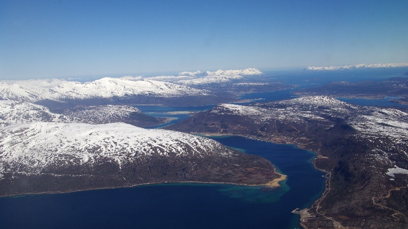 Nous survolons les fjords où la mer est encore prise par les glaces et les sommets très enneigés. Vol Oslo - îles Lofoten