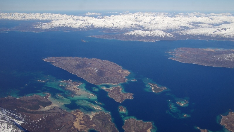 Nous survolons les fjords où la mer est encore prise par les glaces et les sommets très enneigés. Vol Oslo - îles Lofoten
