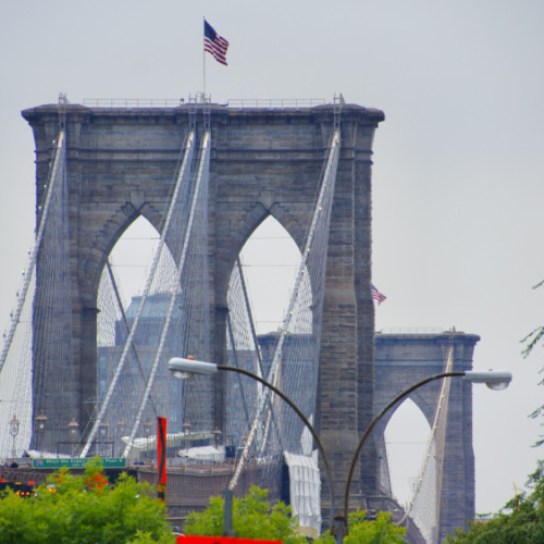 Pont de Brooklyn avec drapeaux américains, journée nuageuse. Pont de Brooklyn avec drapeaux américains, journée nuageuse.