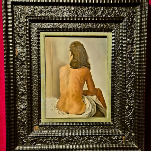 Gala nue vue de dos se regardant dans un miroir invisible. Les toiles du Théâtre Musée Dalí.